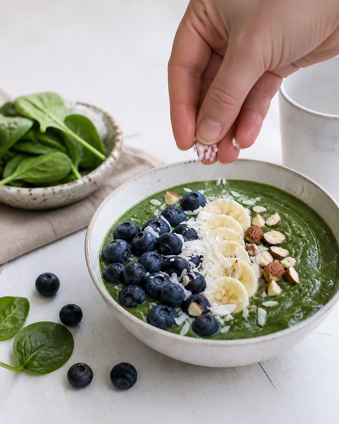 Fresh finished smoothie bowl med blåbær og spinat receiving its final garnish under tilberedningen af smoothie bowl med blåbær og spinat