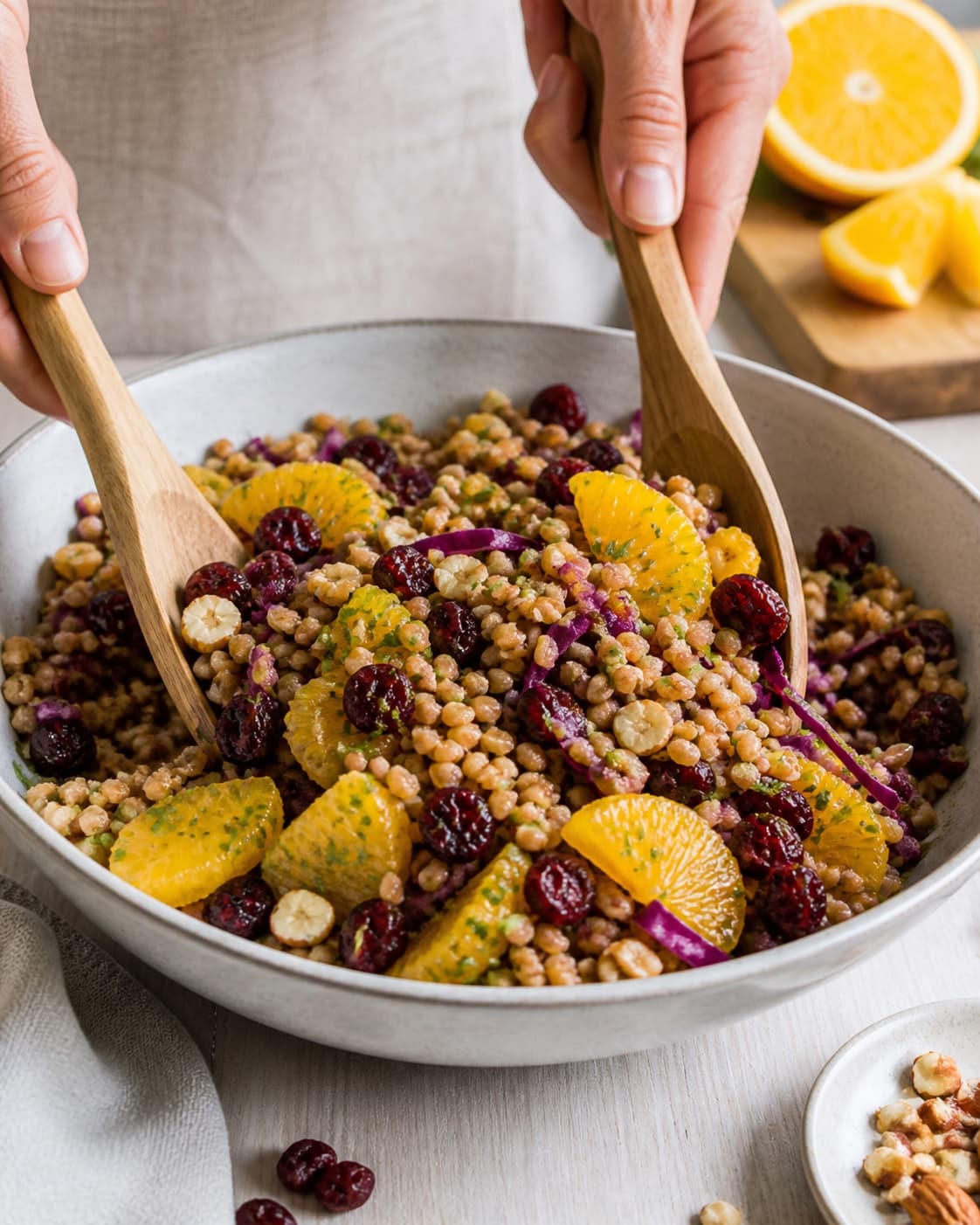 speltsalat med appelsin og tørrede tranebær being gently combined without crushing the ingredients under tilberedningen af speltsalat med appelsin og tørrede tranebær