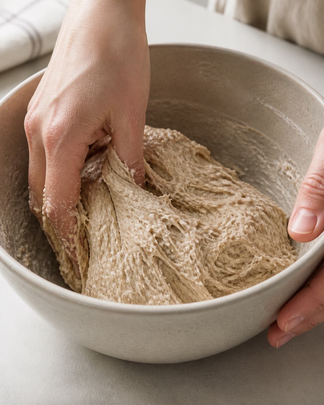 Close view of the moist dough for fuldkornspitabrød being mixed in a bowl with hvedemel, lunkent vand, gær, fint salt under tilberedningen af fuldkornspitabrød