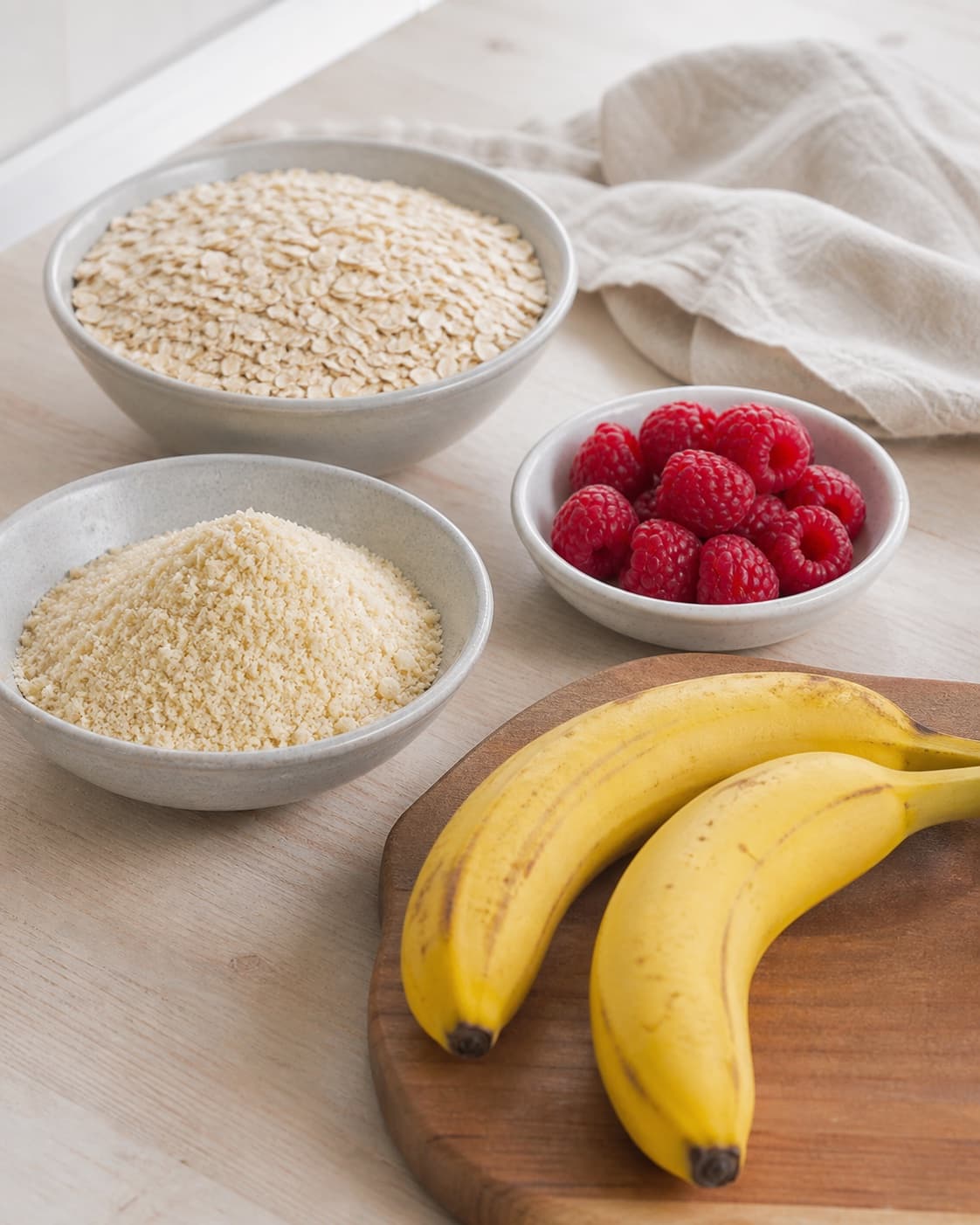 Gluten-free oat flour almond meal and baking powder prepared beside whole raspberries under tilberedningen af sunde hindbærmuffins