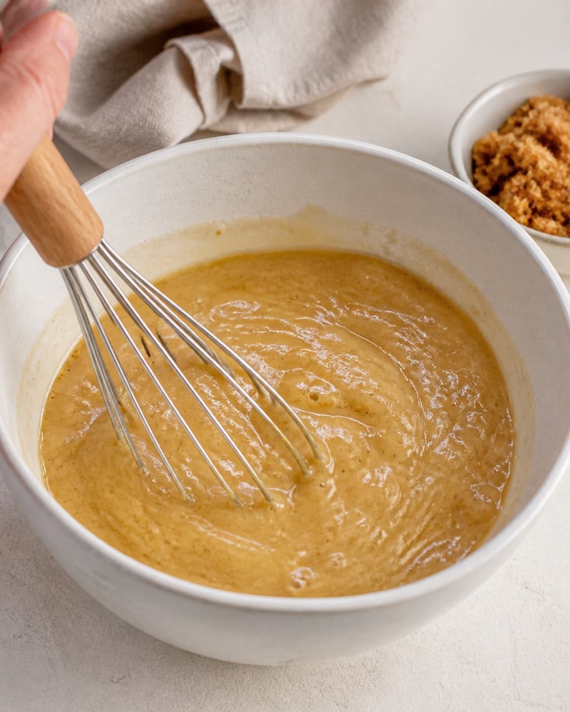 Mashed banana eggs rapeseed oil and brown sugar being whisked into a glossy base under tilberedningen af sund banankage med chokolade