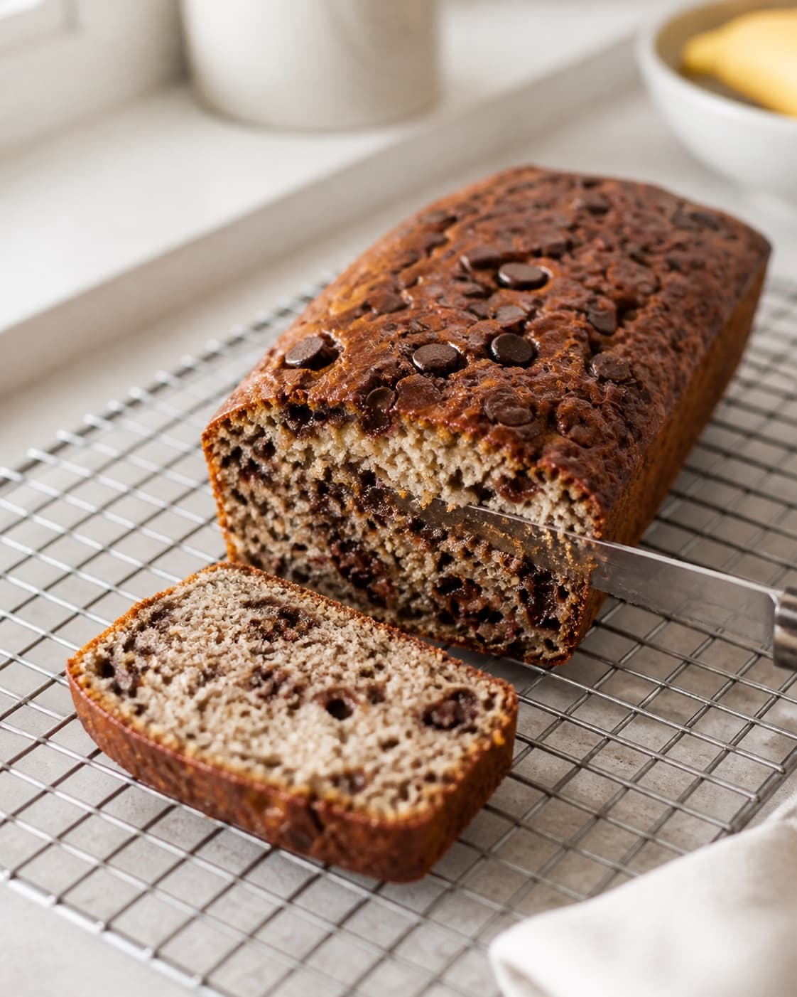 Banana chocolate cake cooling before a clean slice reveals the moist crumb under tilberedningen af sund banankage med chokolade
