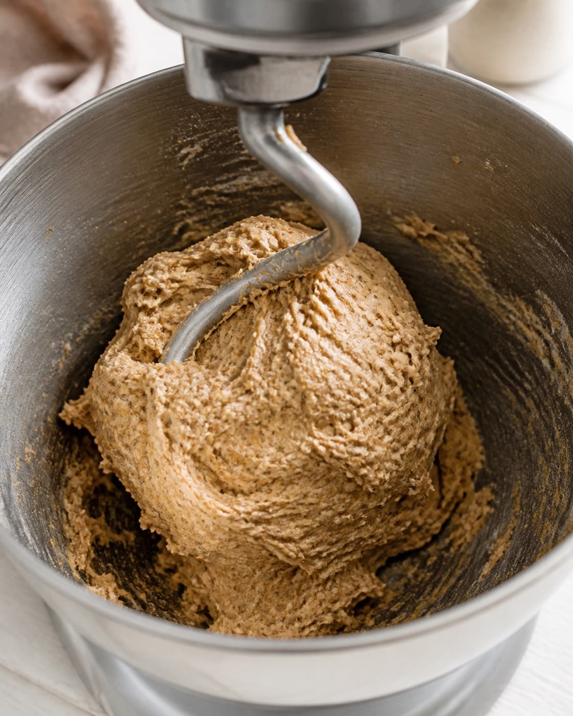 Wholegrain burger bun dough with yeast honey water oil flour and salt coming together under tilberedningen af grove burgerboller med sesam