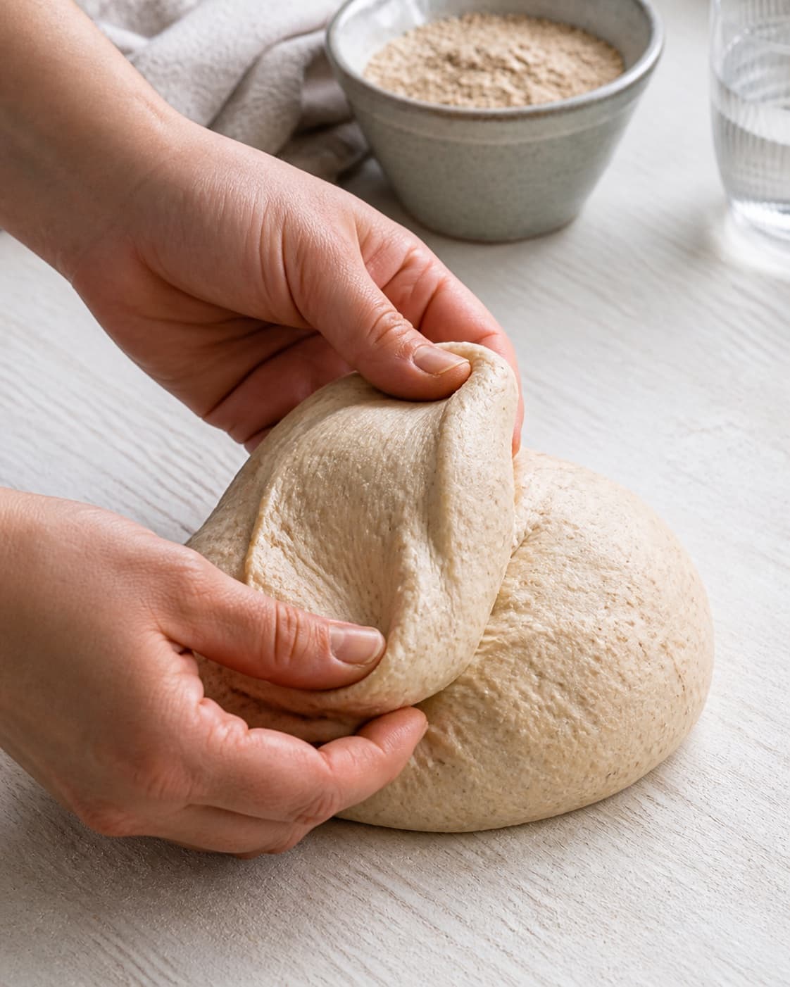 Elastic wholegrain burger bun dough stretching into a thin windowpane under tilberedningen af grove burgerboller med sesam