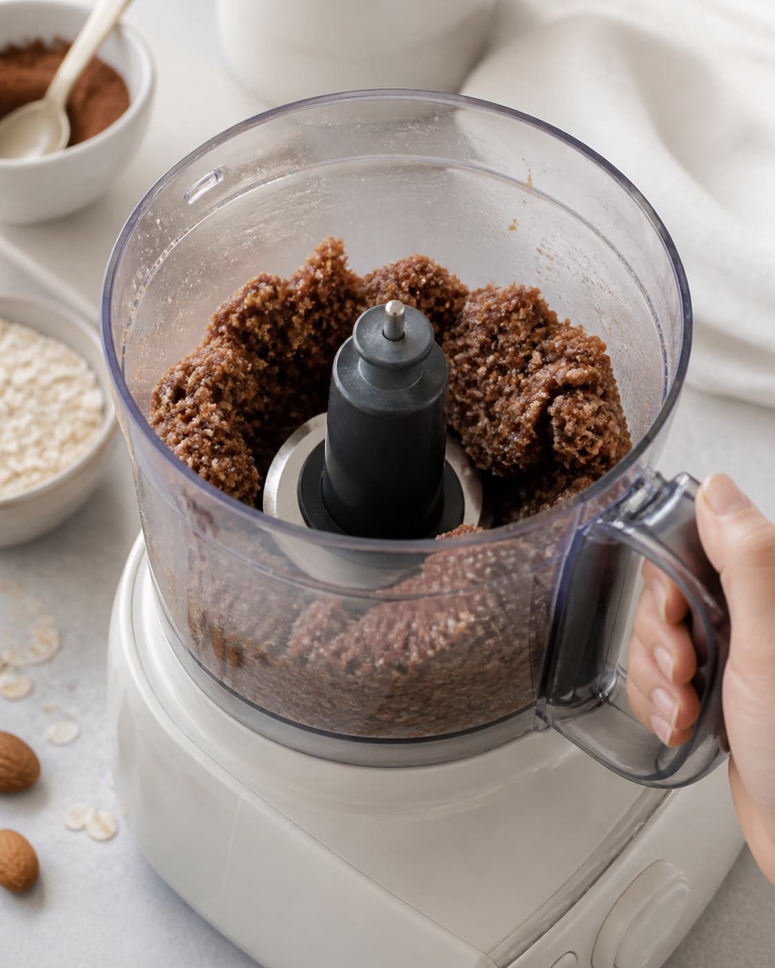 Dates coconut oil and vanilla binding the cocoa almond oat crumb into a cohesive mass under tilberedningen af dadelkugler – en grundopskrift