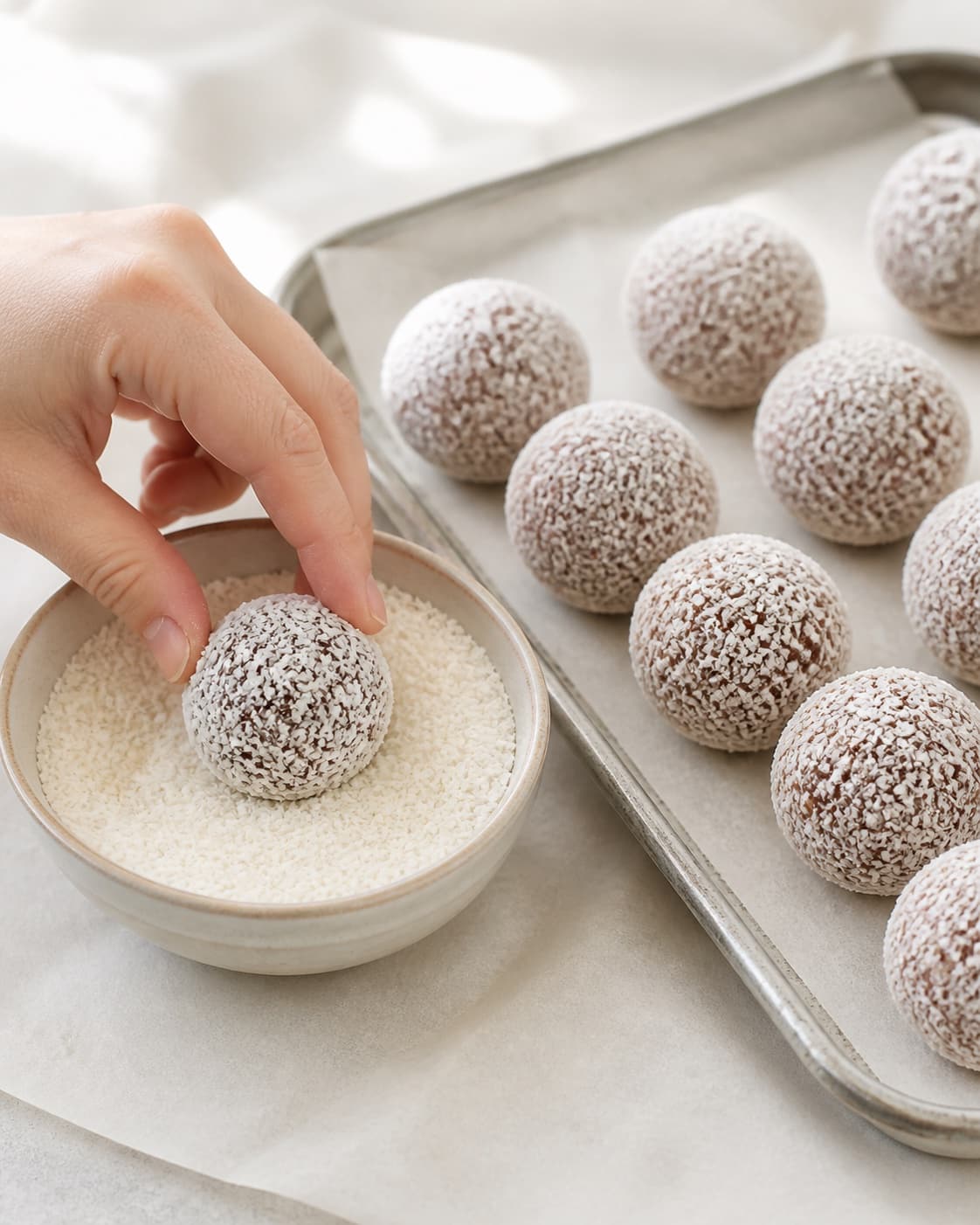 Fresh date cocoa balls being rolled in a thin even coconut coating before chilling under tilberedningen af dadelkugler – en grundopskrift