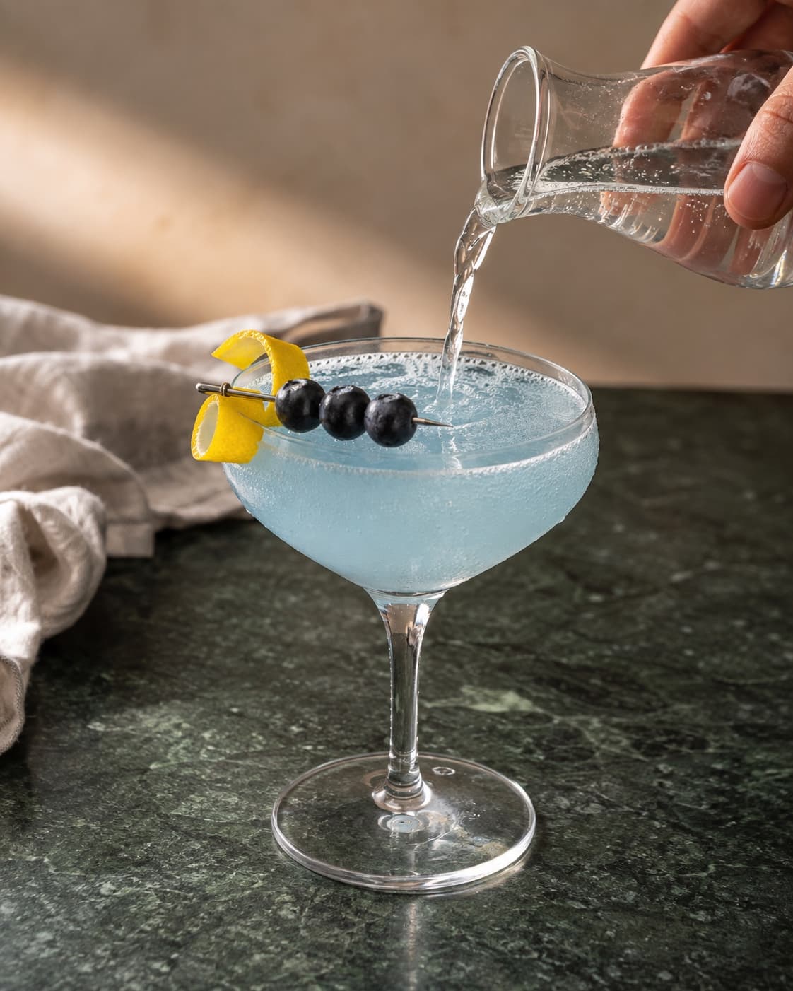 Lyseblå Astronaut drink toppes med brus og pyntes med citron og blåbær