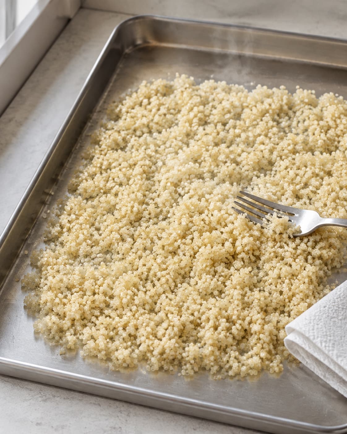 Kogt quinoa bredes ud og damper tør med løse korn og synlige små spiraler
