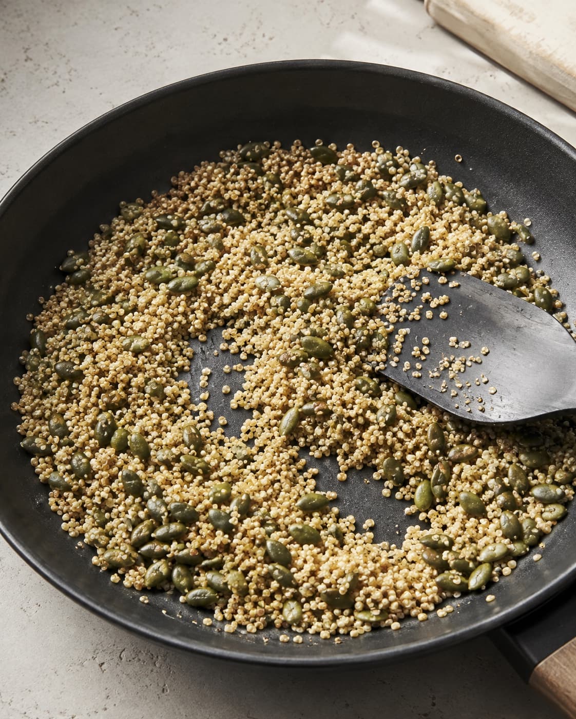 Tør quinoa og græskarkerner ristes i et tyndt lag til spredt gyldne og sprøde
