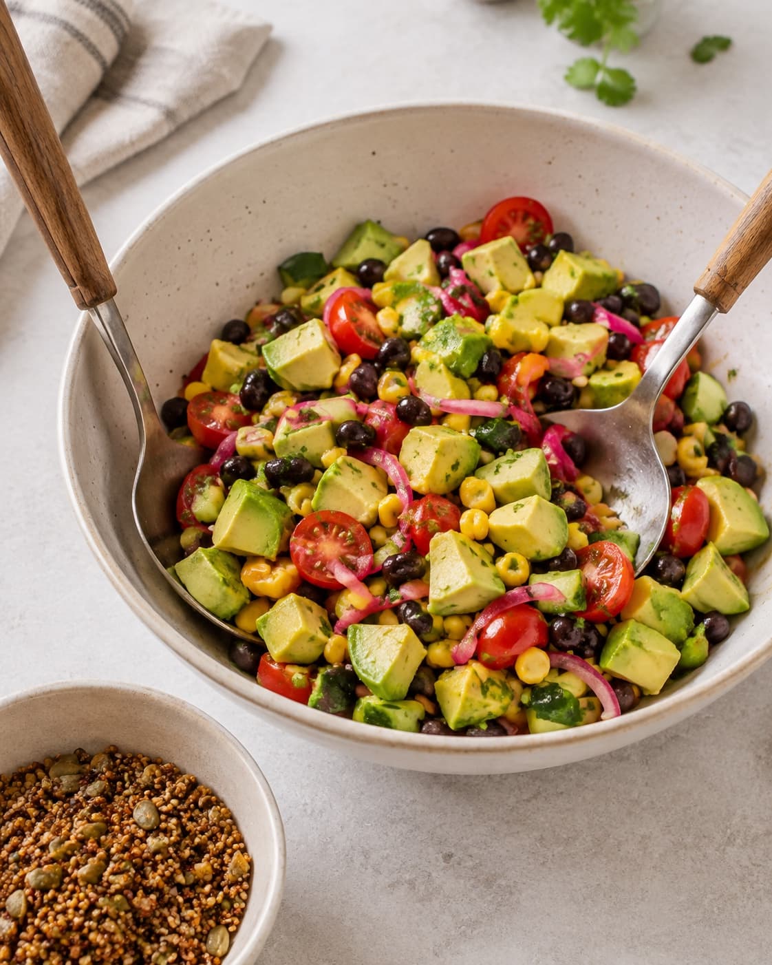 Avocado foldes forsigtigt i bønner, majs og grønt, før sprød quinoa lægges øverst