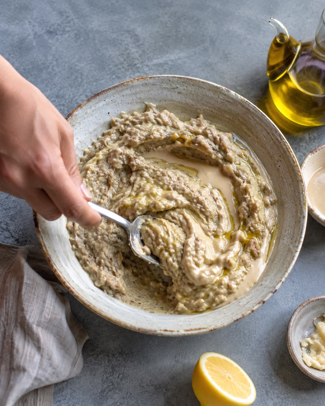 Baba ganoush foldes med tahin og citron og pyntes med olie, persille og granatæble