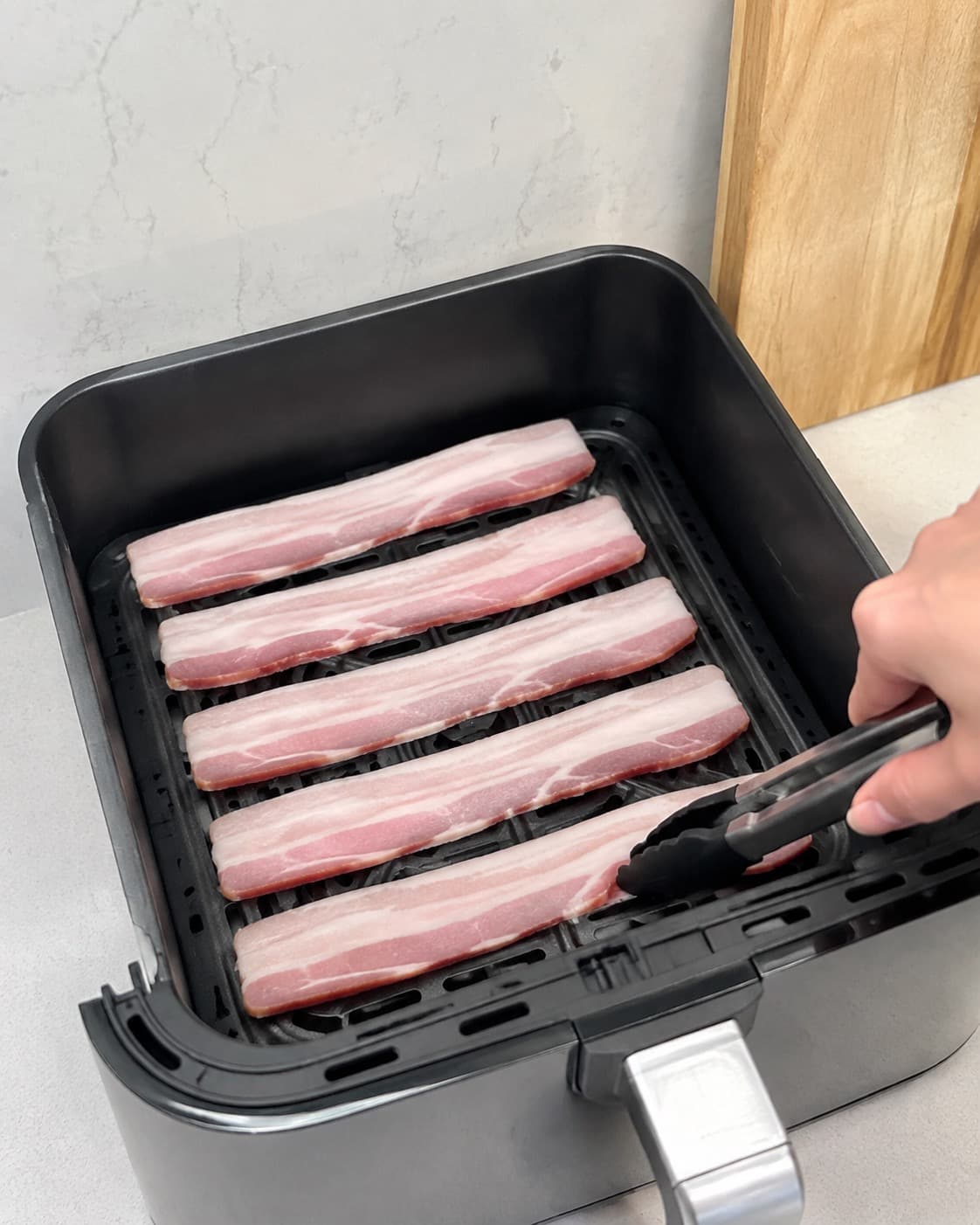 Rå baconskiver lægges i ét lag uden overlap i en åben airfryer-kurv