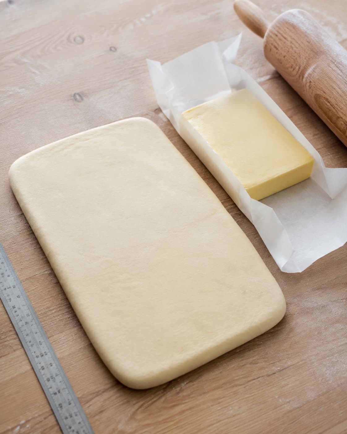Kold croissantdej og en ensartet firkantet smørplade ligger separat klar til laminering