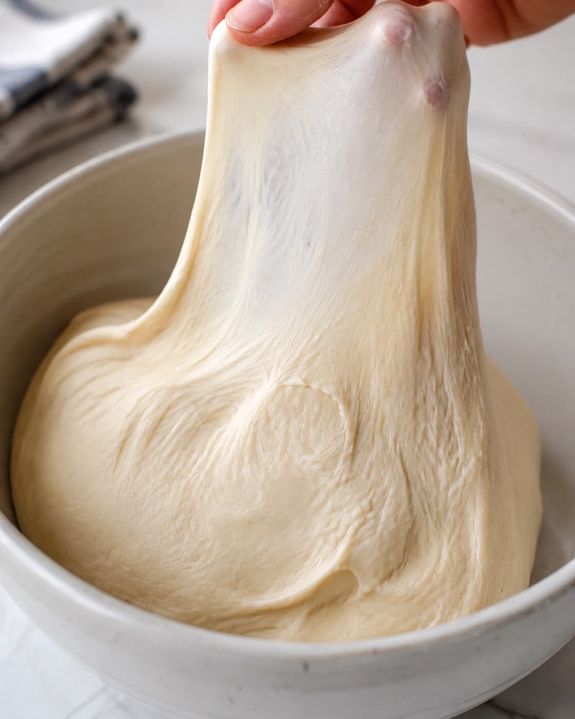 Smidig gærdej til kanelsneglekage trækkes til et tyndt glutenvindue