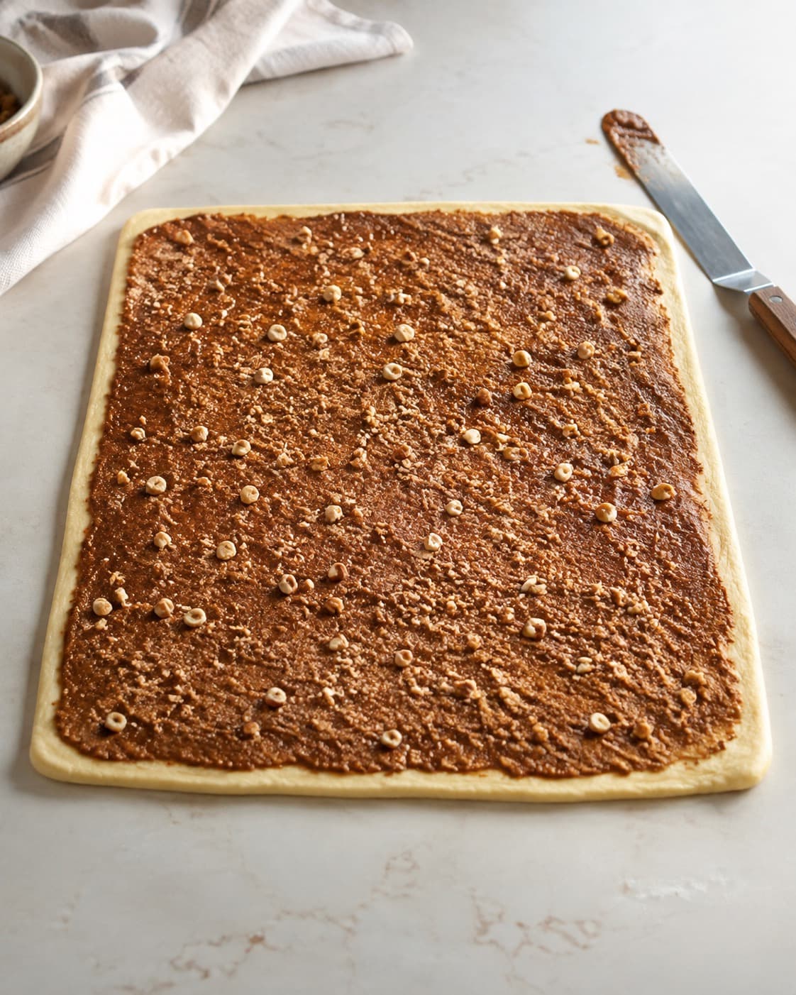 Kanelremonce med brunet smør og hasselnødder fordeles på udrullet dej