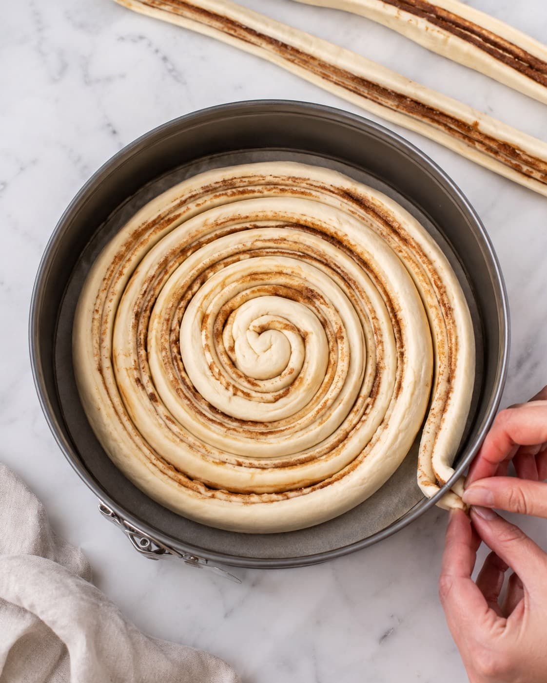 Lange dejstrimler med kanelfyld vikles til én stor spiral i en springform