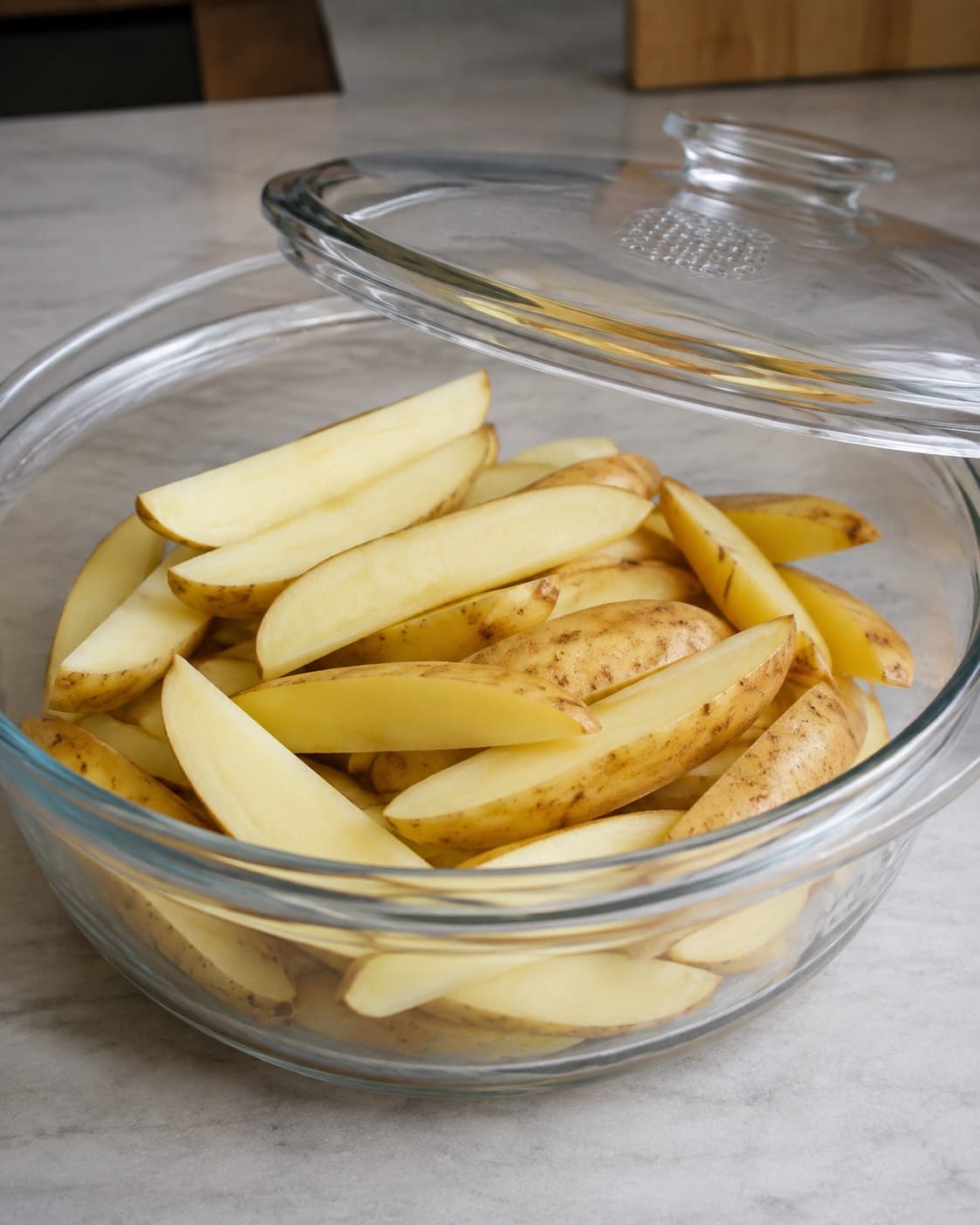 Ens rå kartoffelbåde med lidt vand i en ventileret glasskål