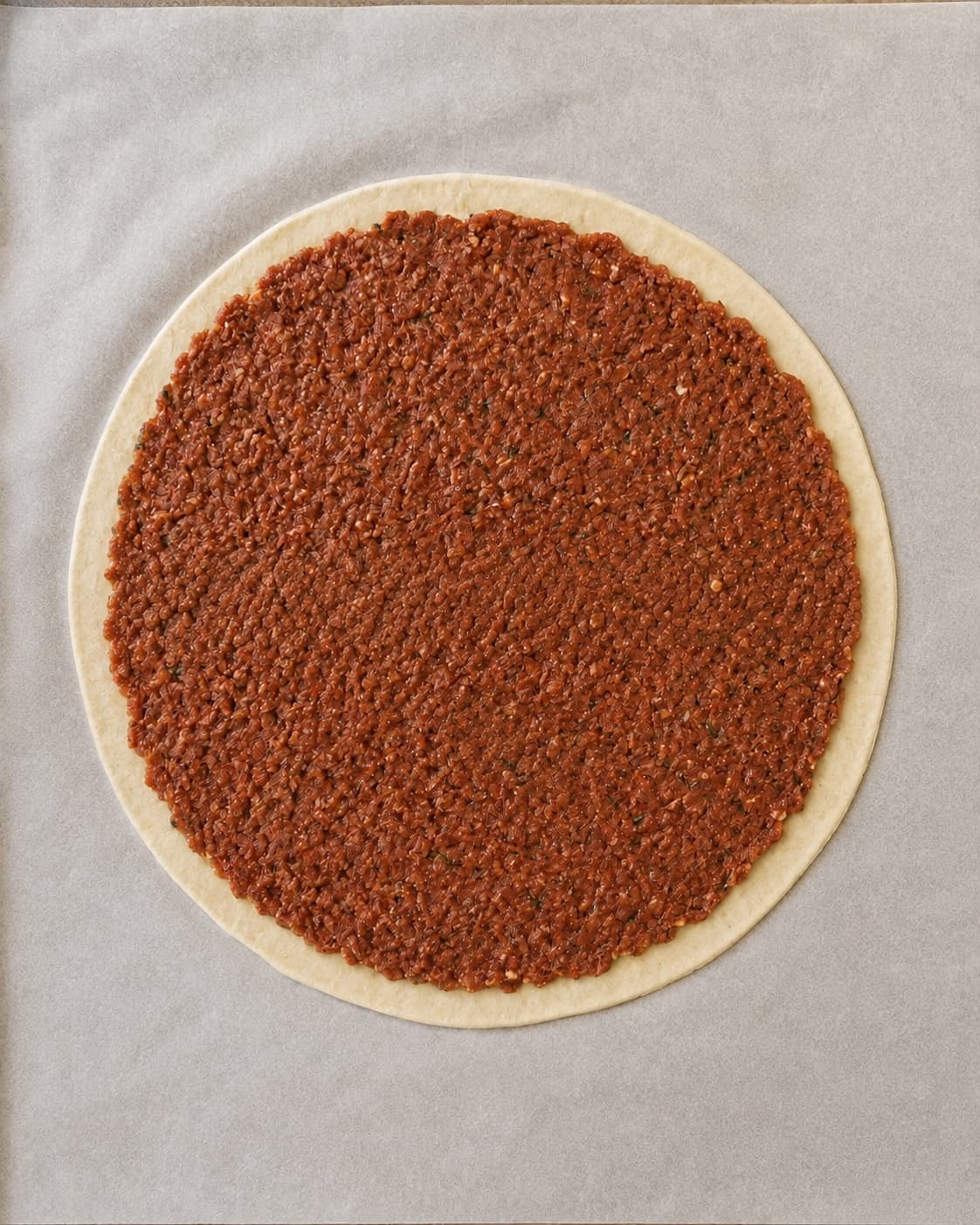 Lahmacun rulles til 28 centimeter og dækkes med 3 millimeter lammefyld