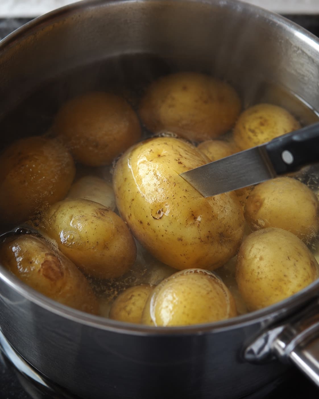 Små kartofler simrer, mens en kniv kontrollerer den største kartoffels mørhed