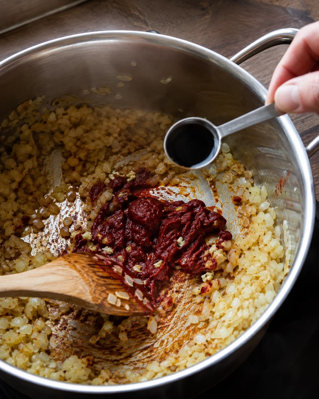 Tomatpuré og hvidløg ristes i gyldne løg før balsamico tilsættes