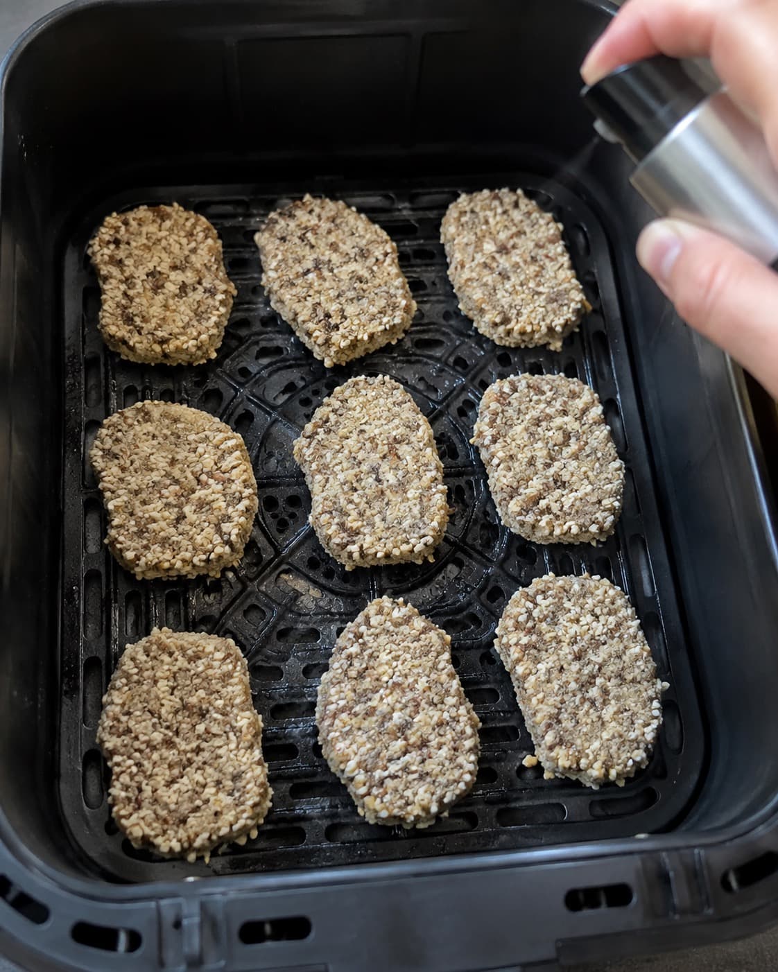 Råt panerede nuggets ligger med afstand i airfryer-kurv og sprayes let med olie