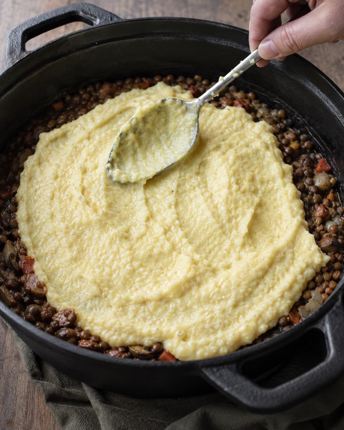 Cremet parmesanpolenta fordeles over linseragout og bages til en gylden bølget top