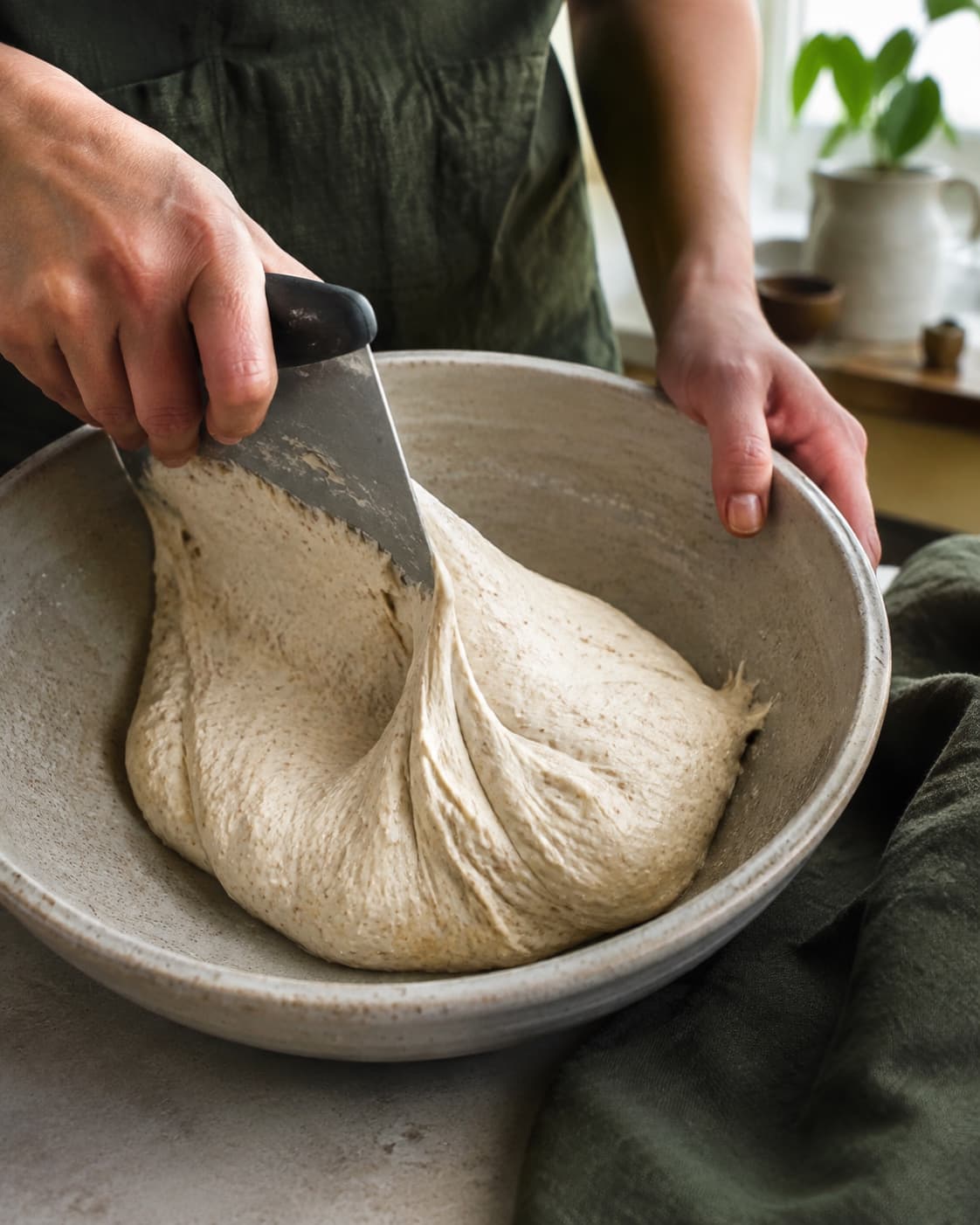 Let klistret pizzadej foldes elastisk med en dejskraber i stor skål