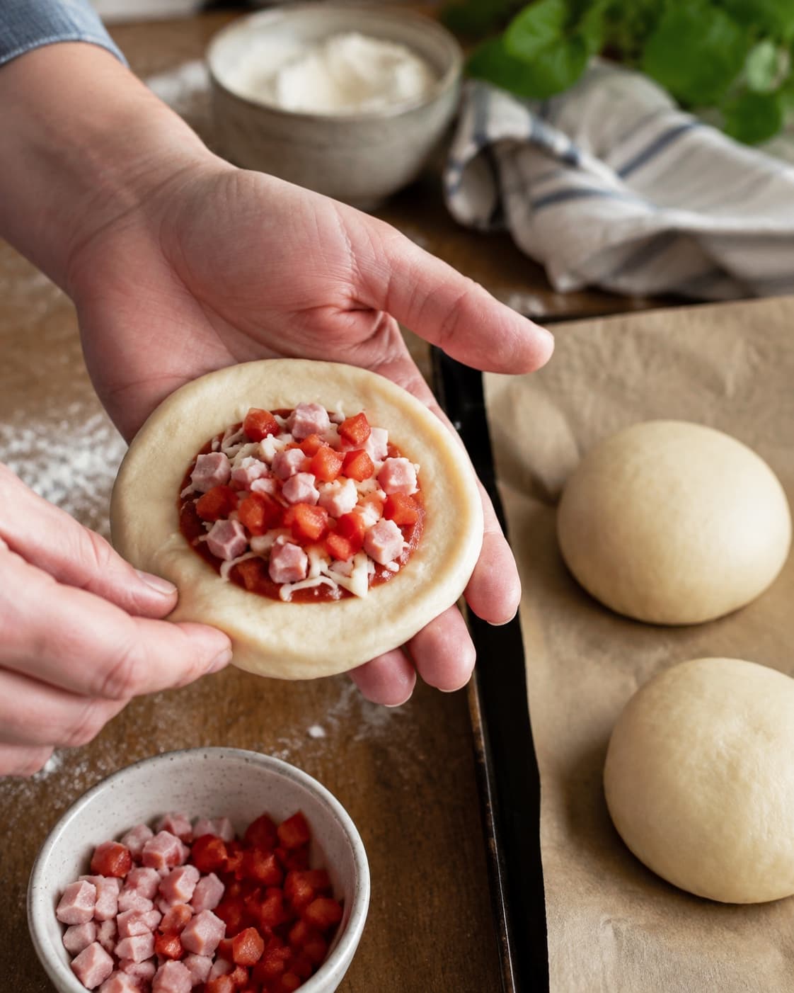Dejskive fyldes sparsomt med tomat, mozzarella, skinke og rød peber