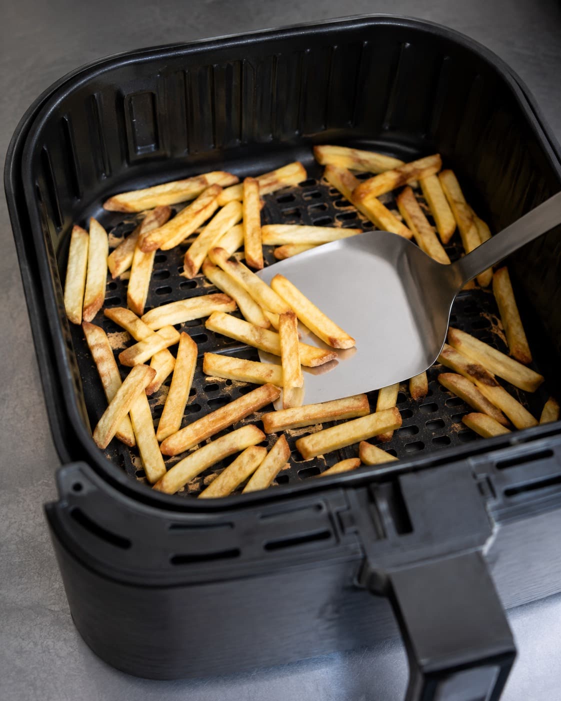 Lysegyldne kartoffelstave vendes luftigt i airfryer efter første varmefase
