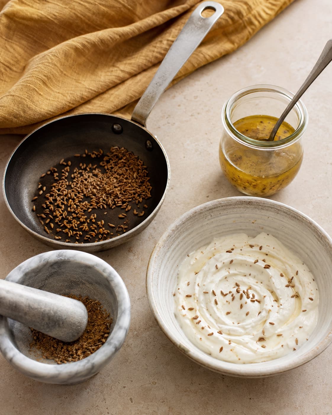 Ristet spidskommen knuses og deles mellem blank limedressing og tyk yoghurt