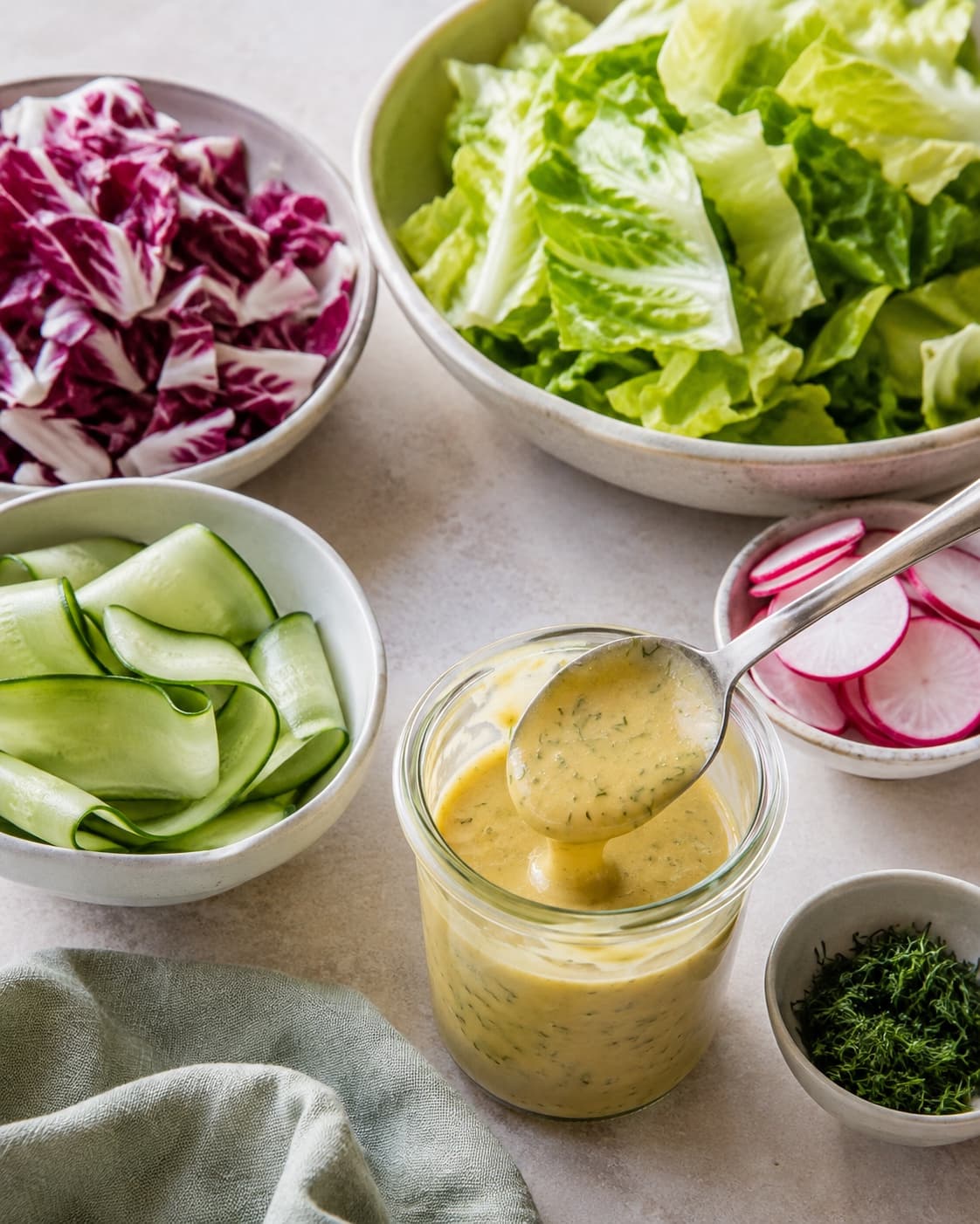 Blank senneps-citrondressing står ved siden af tørre snittede salatgrøntsager