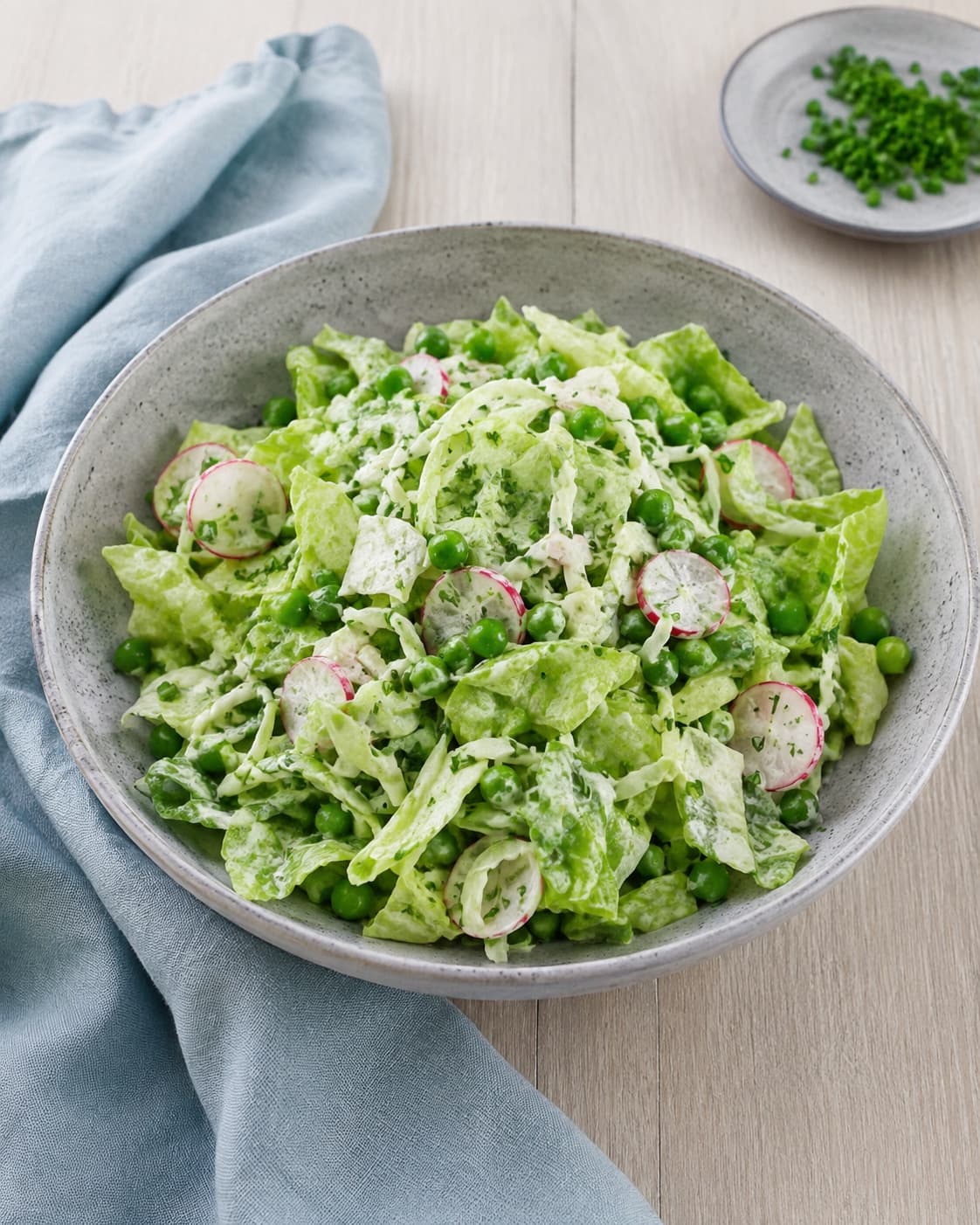 Grov mormorsalat med salat, spidskål, ærter og radiser vendes let i citronfløde