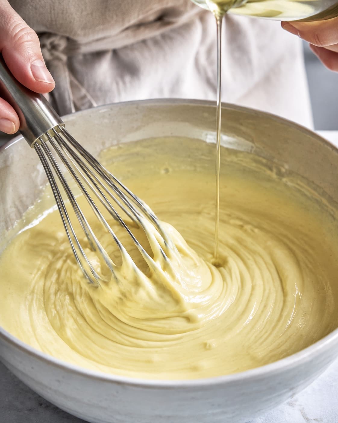 Neutral olie piskes i tynd stråle til en blank mayonnaise der holder spor