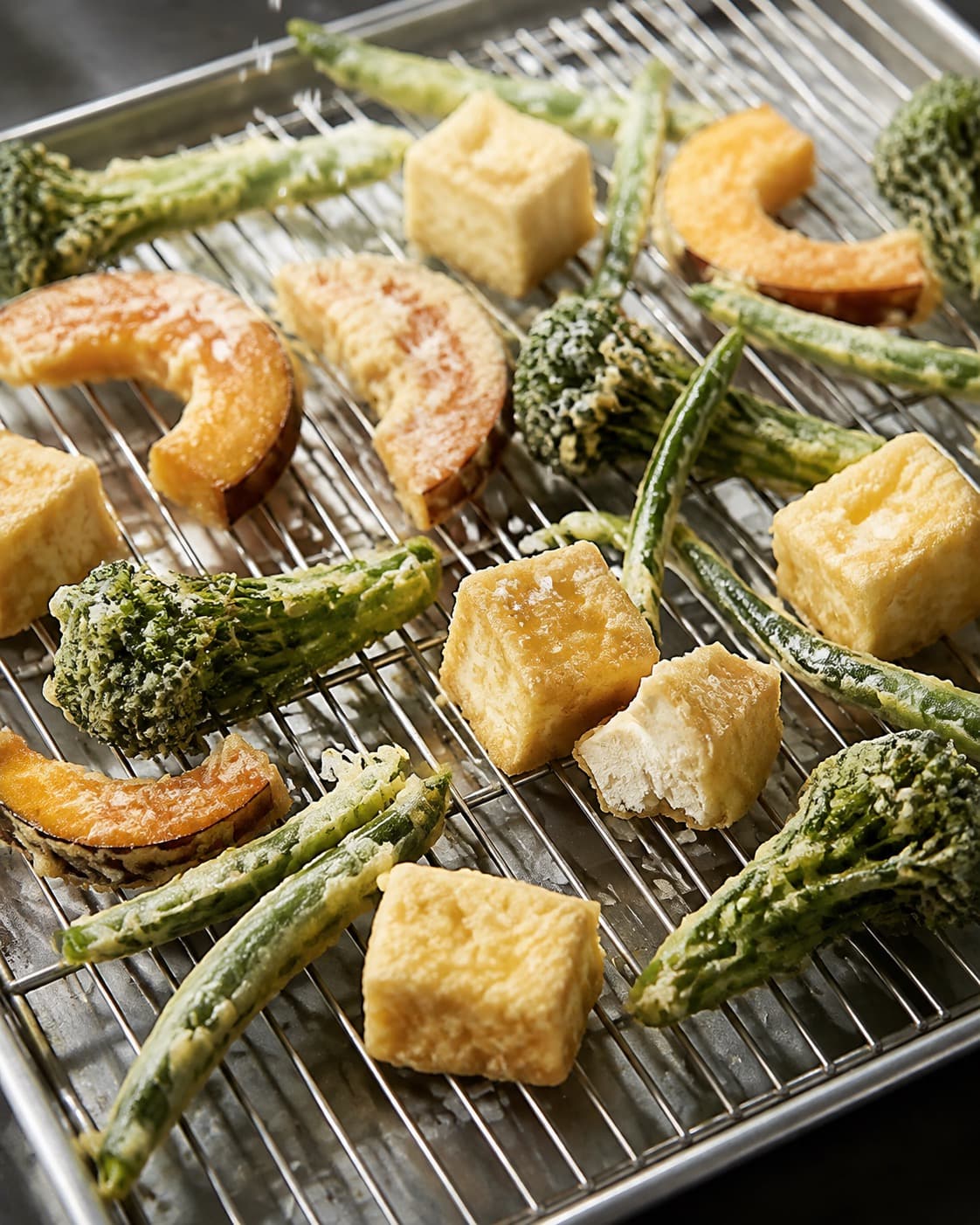 Bleggylden tempura drypper af i ét lag på en metalrist