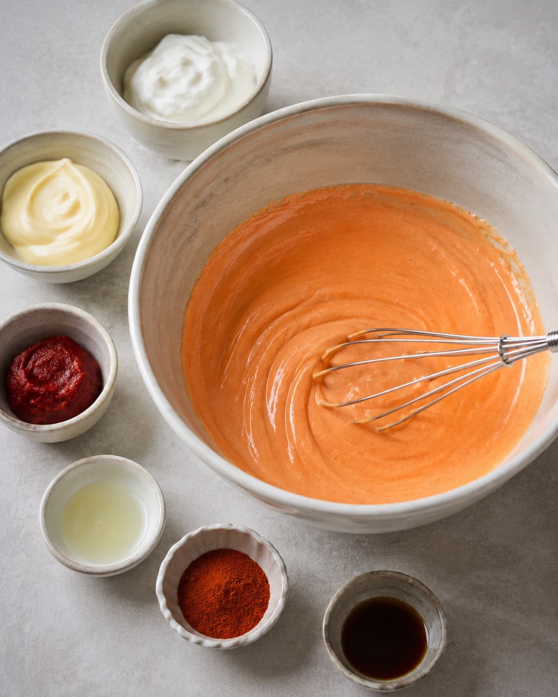 Mayonnaise, skyr, tomatkoncentrat, citron og krydderier piskes til en glat koral-orange base