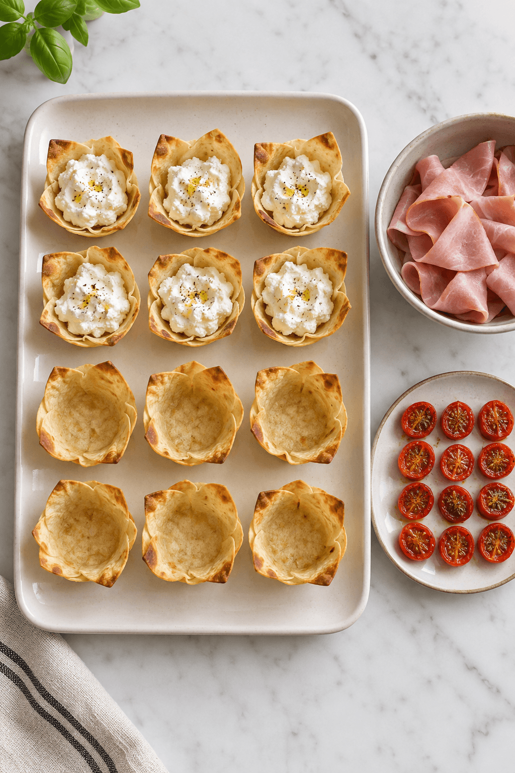 Tolv tortillaskåle under samling med ricotta, skinke og bagte tomater